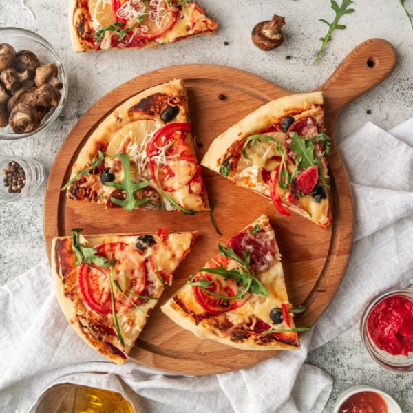 Four slices of Pizza King of Irving pizza with various toppings on a wooden board.