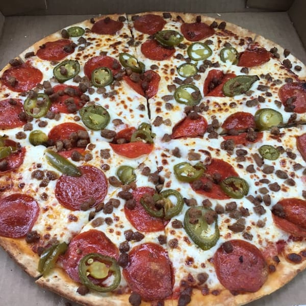 A Pizza King of Irving pizza with pepperoni, sausage, and jalapeños in a box.