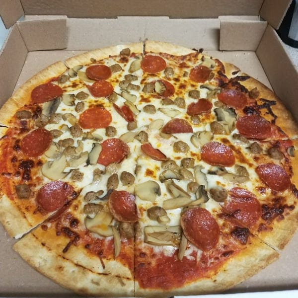 A Pizza King of Irving pizza with pepperoni, sausage, and mushrooms in a cardboard box.