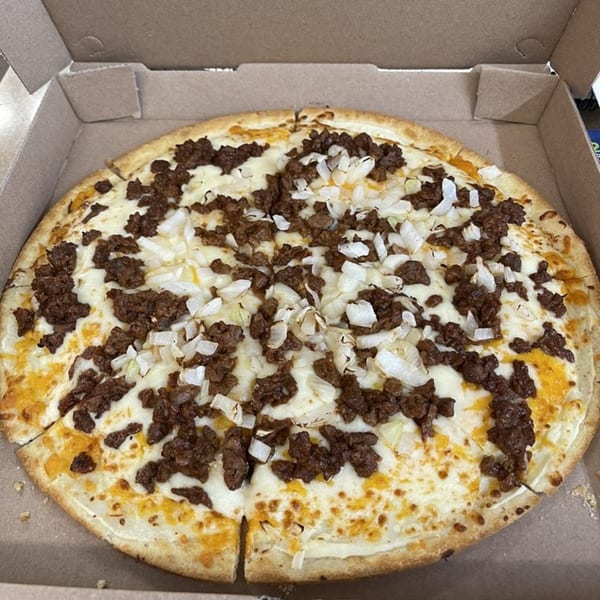 A Pizza King of Irving pizza with white sauce, ground beef, and diced onions in a box.